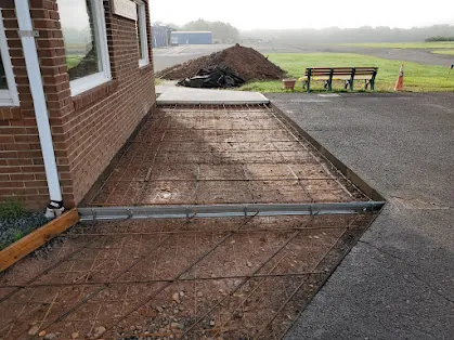 Reinforcing steel and formwork prepared for a concrete apron beside a Somerset Airport building