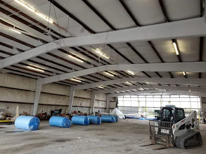 Insulation installation underway inside a Somerset Airport hangar with insulation rolls staged on the floor