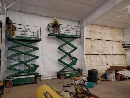 Reese Enterprises crew installing wall insulation from scissor lifts inside a Somerset Airport hangar